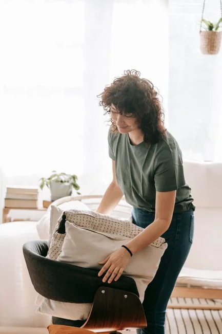 why-choose-us A hotel housekeeper carefully arranges clean towels in an elegant room setting.